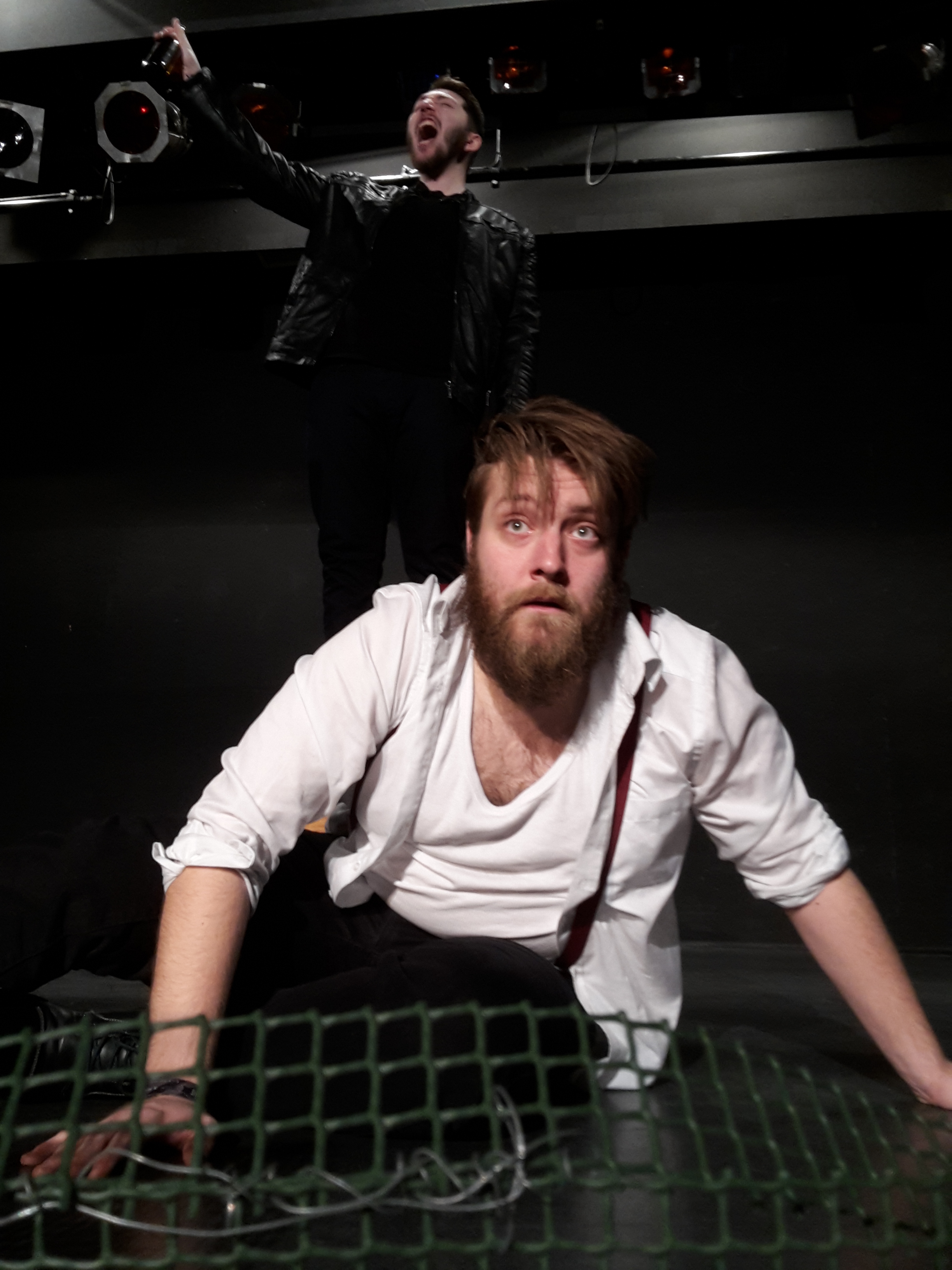 Szenenfoto: Woyzeck kauert auf dem Boden; der Tambourmajor gröhlt im Hintergrund